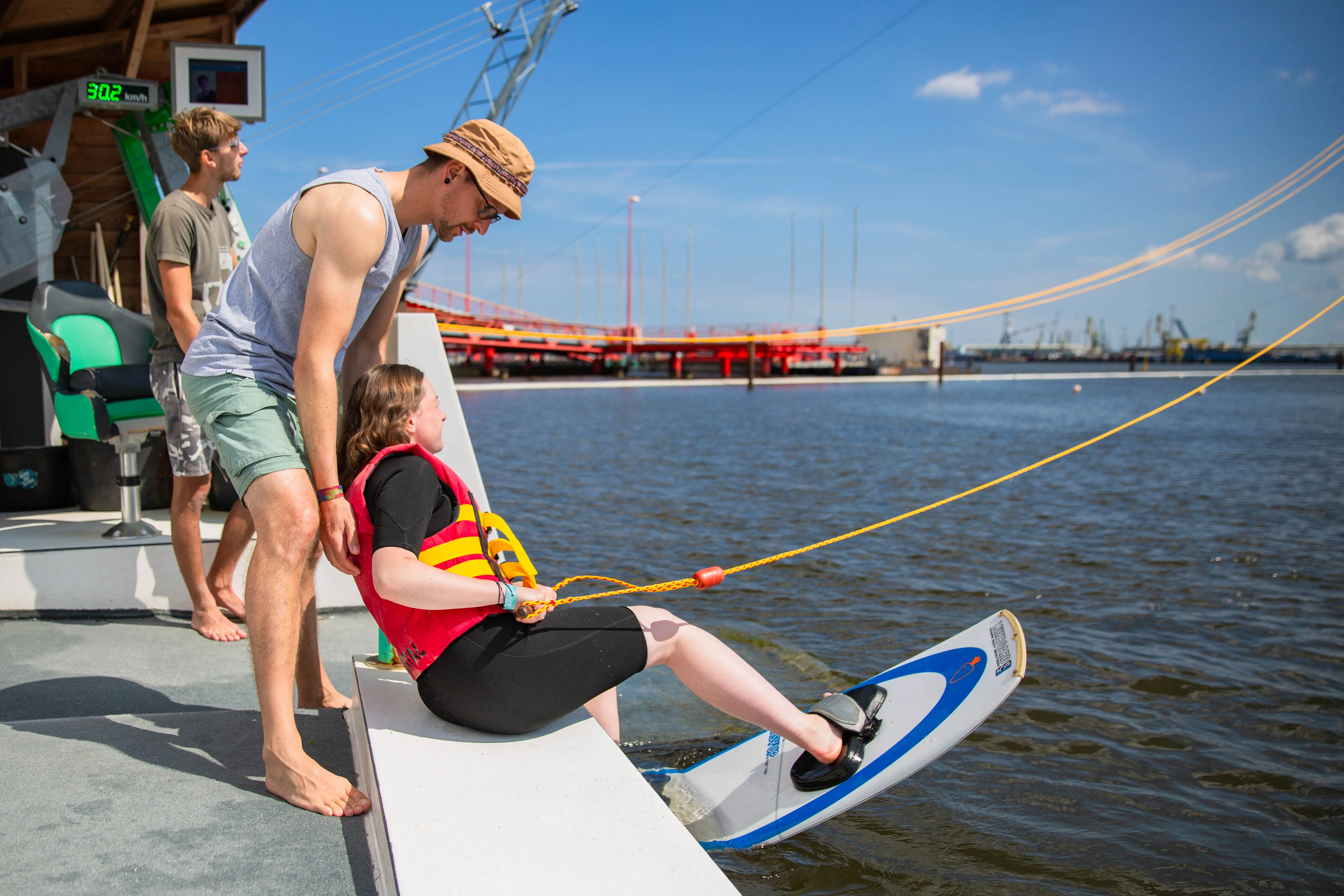 Kind bekommt beim Schüler-Ferien-Kurs Starthilfe am Wakeboard-Cable
